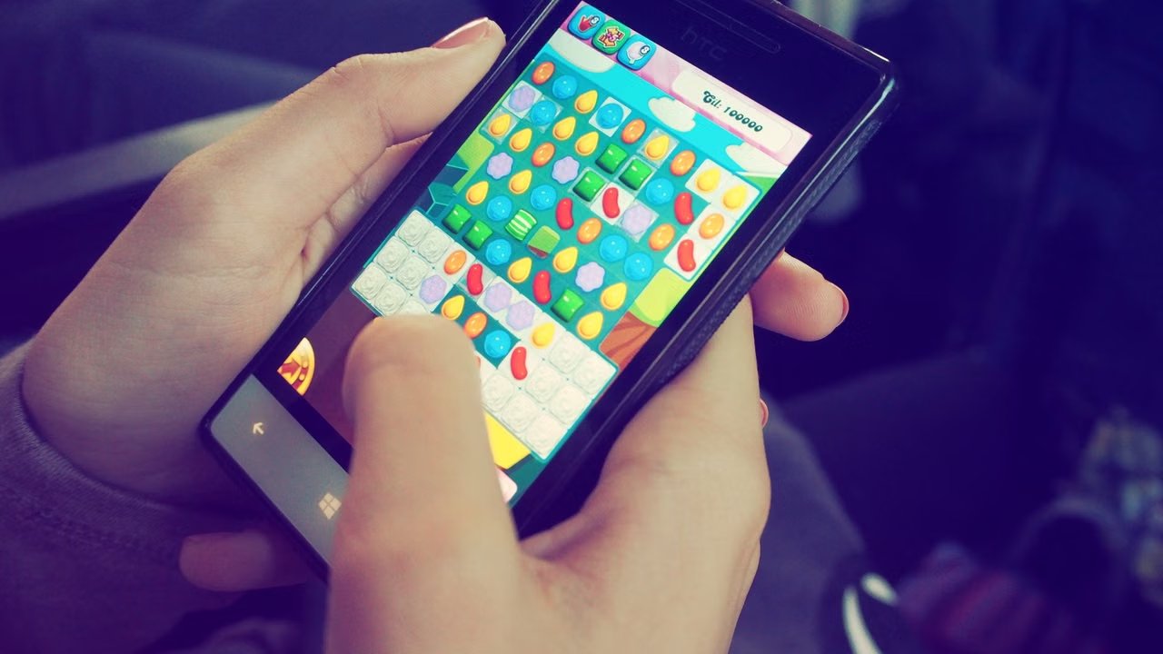 Hands playing a colorful match-3 arcade game on a smartphone