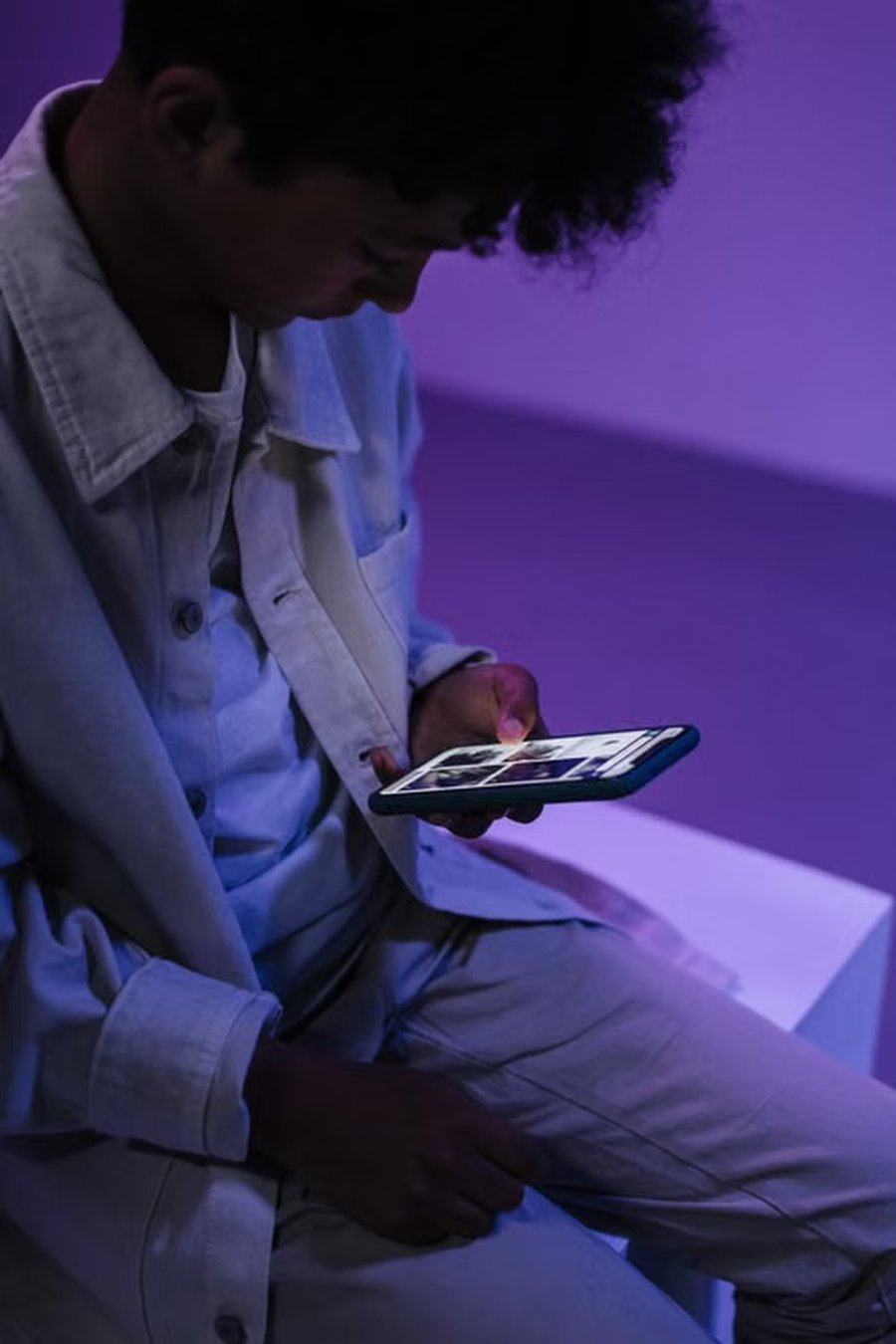 Player focused on a mobile arcade game in a neon-lit room